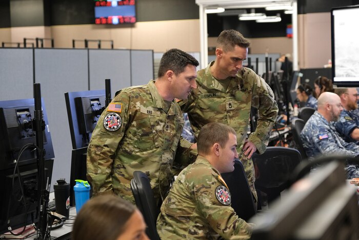 uniformed military members flying flight simulators