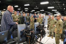 uniformed military members and civilians talk while standing in semicircle