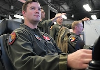 uniformed U.S. Airmen fly MQ-9 simulators