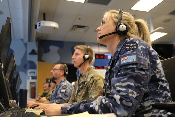 military members work at computers while wearing headsets