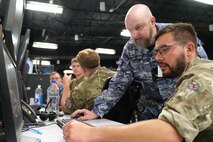 uniformed military members working at a computers