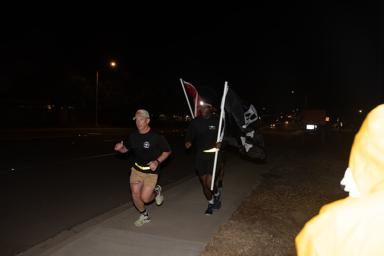 U.S. Marine Corps Capt. Tyler Chittick, front, a KC-130J Super Hercules pilot, and Marines with Marine Aerial Refueler Transport Squadron (VMGR) 352, Marine Aircraft Group 11, 3rd Marine Aircraft Wing, conduct a Veteran's Day flag run at Marine Corps Air Station Miramar, California, Nov. 7, 2024. The run, spearheaded by Capt. Tyler Chittick, began at MCAS Miramar and will end at the School of Infantry West, Marine Corps Base Camp Pendleton totaling 55 miles of relay run and hike. Each year Chittick brings Marines together to complete a challenging physical activity in honor of fallen and disabled veterans including a fellow Marine who was injured by an improvised explosive device in Afghanistan in 2011. (U.S. Marine Corps photo by Gunnery Sgt. Antonio De La Fuente)