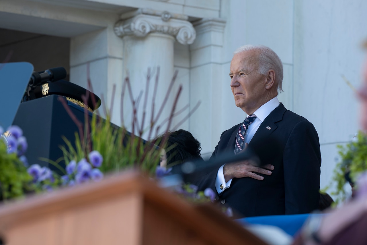 The president stands in front of a lectern while putting his hand over his heart.