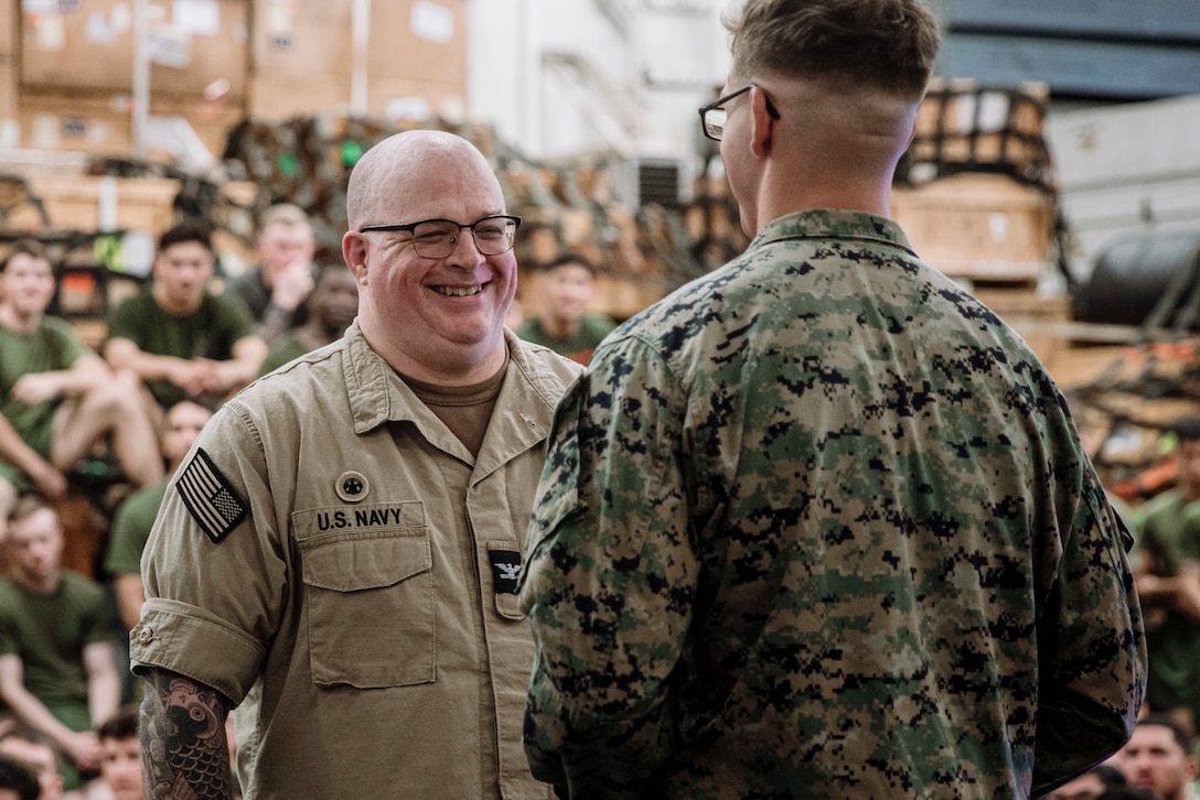 U.S. Navy Capt. Tate Robinson, left, Commodore of Amphibious Squadron 5 and the oldest Marine present during the 15th Marine Expeditionary Unit cake cutting ceremony, speaks to the youngest Marine, U.S. Marine Corps Lance Cpl. Carson Pash, a machine gun team leader assigned to Bravo Company, Battalion Landing Team 1/5, 15th Marine Expeditionary Unit, aboard the amphibious assault ship USS Boxer (LHD 4) in the Pacific Ocean Nov. 10 2024. Before commissioning in the Navy, Robinson enlisted in the Marine Corps as a rifleman in 1991. The cake cutting ceremony was held on the second day of the 15th MEU’s 249th Marine Corps birthday celebrations as Boxer transited past the international dateline. Elements of the 15th MEU are currently embarked aboard Boxer and are conducting routine operations in U.S. 3rd Fleet. (U.S. Marine Corps photo by Sgt. Amelia Kang)