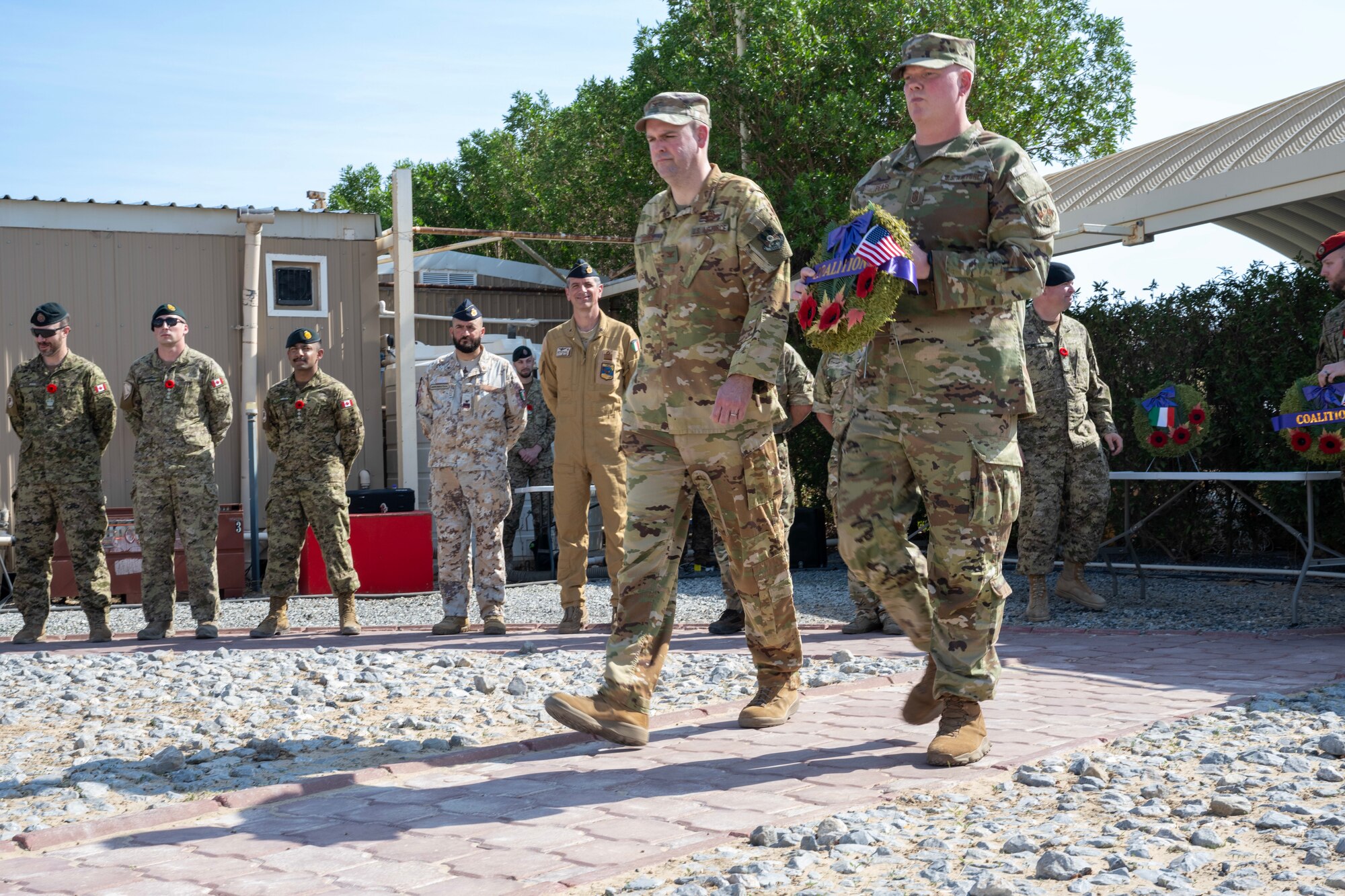 Two service members carry a wreath during a Remembrance Day ceremony.