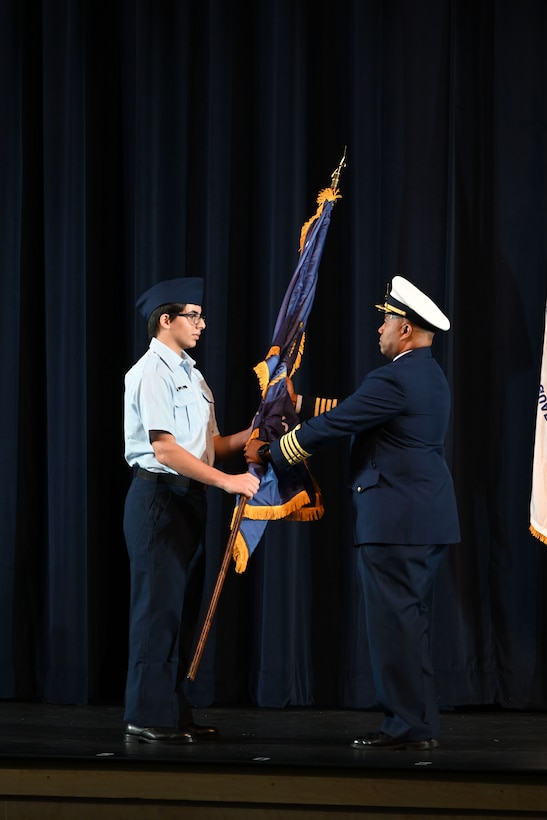 Coast Guard Capt. Willie Carmichael, chief of staff of Coast Guard Seventh District, passes the guidon to a Innovation High School lead JROTC cadet during the Coast Guard Junior Reserve Officers' Training Corps (JROTC) unit establishment ceremony at Innovation High School Orlando, Florida, Nov. 8, 2024. Innovation High School’s Coast Guard JROTC unit is the 12th in the nation and is the largest to-date, with over 190 cadets enrolled in the inaugural semester. (U.S. Coast Guard photo by Petty Officer 1st Class Riley Perkofski)