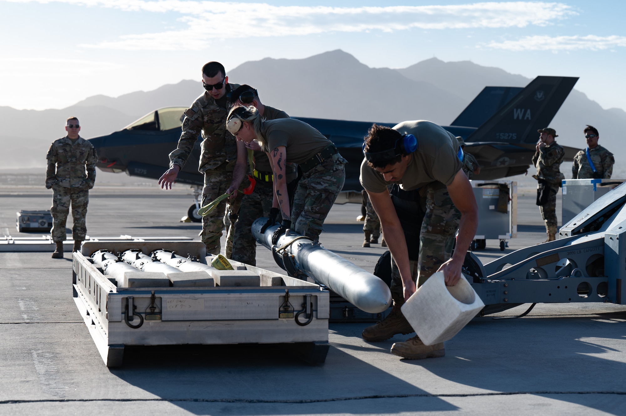 Airmen lift a munition onto a lift truck.
