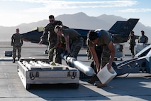 Airmen lift a munition onto a lift truck.