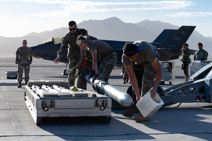 Airmen lift a munition onto a lift truck.