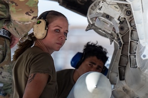 An Airman looks at the camera while loading a munition on an F-35A Lightning II.