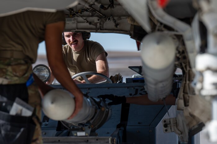 An Airman driving a lift helps load a missile on an F-35A Lightning II.