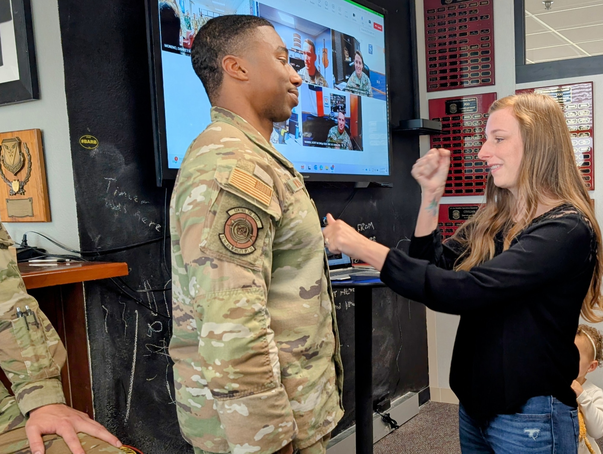 Woman places patch on mans uniform.