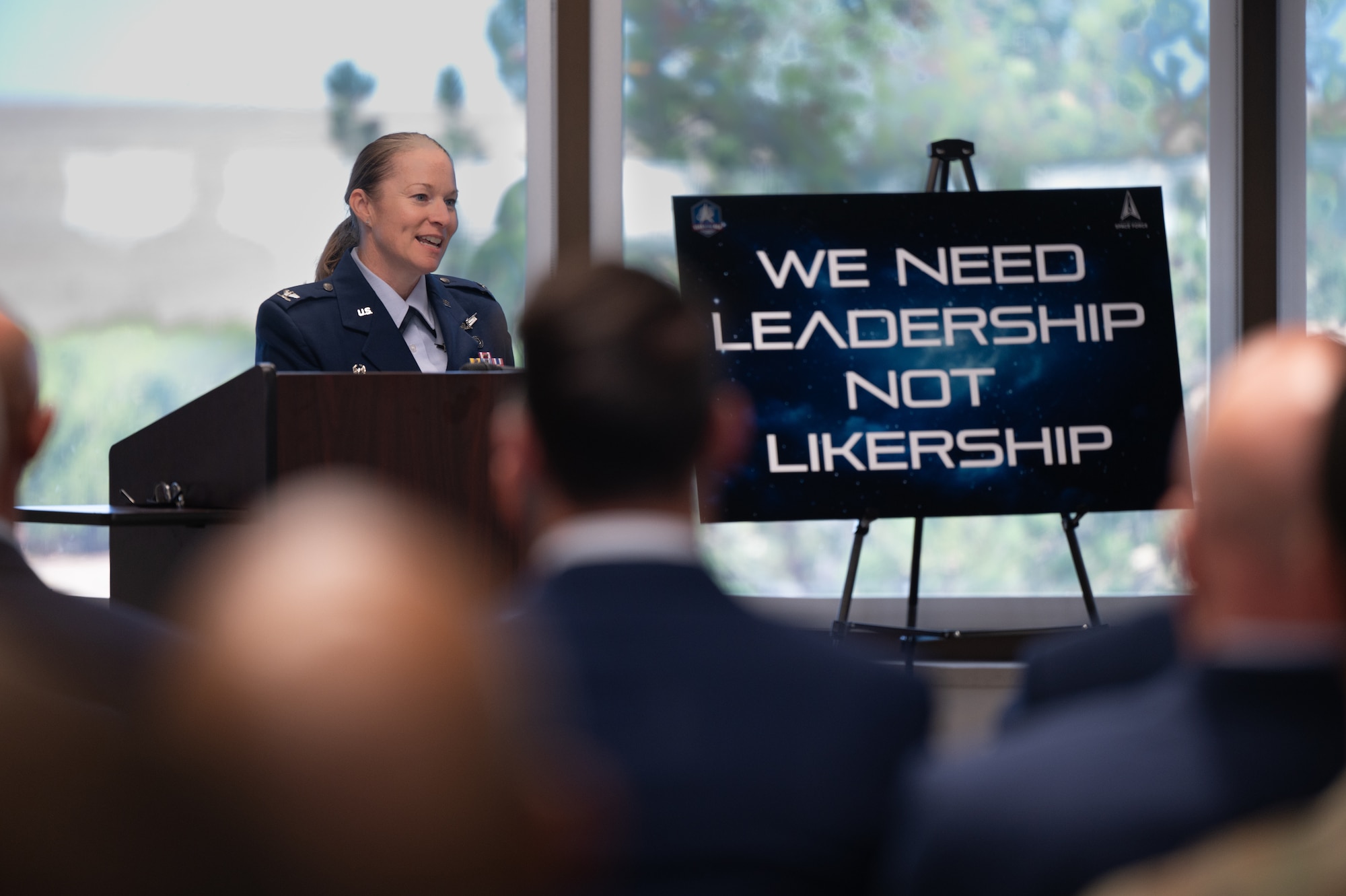 An individual stands behind a podium and addresses an audience.
