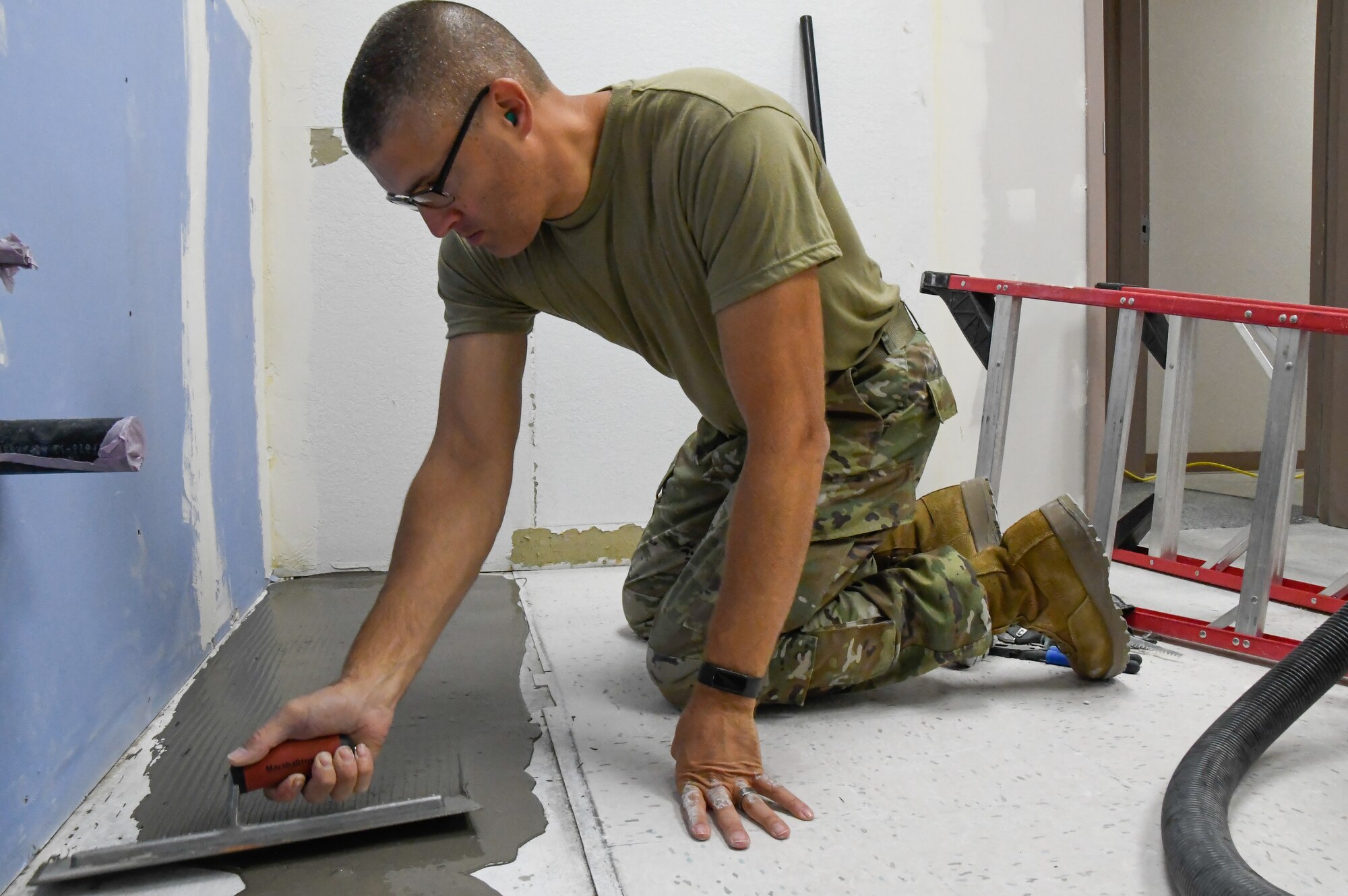 Tech Sgt. Adam Cousin, 168th Civil Engineering Squadron, smooths out cement before installing new flooring in the 168 CE building.
