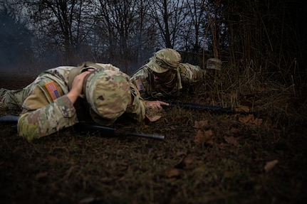 (left-right) Spc. Juan Lopez, a resident of Stillwater, Oklahoma, and Sgt. Bryce Hill, a resident of Tulsa, Oklahoma, assigned to the 1st Battalion, 160th Field Artillery Regiment, 45th Infantry Brigade Combat Team as a signal operations support specialist, and Sgt. Bryce Hill, a resident of Tulsa, Oklahoma, assigned to the 1st Battalion, 179th Infantry Regiment, 45th IBCT as a combat engineer, take cover from simulated indirect fire at the Oklahoma Army National Guard Best Warrior Competition at camp Gruber Training Center, Oklahoma, Nov. 8, 2024.  The OKARNG Best Warrior Competition is an annual event designed to test and recognize the skills, endurance and professionalism of the best Soldiers and NCOs within the organization. (Oklahoma National Guard photo by Spc. Cambrie Cannon)