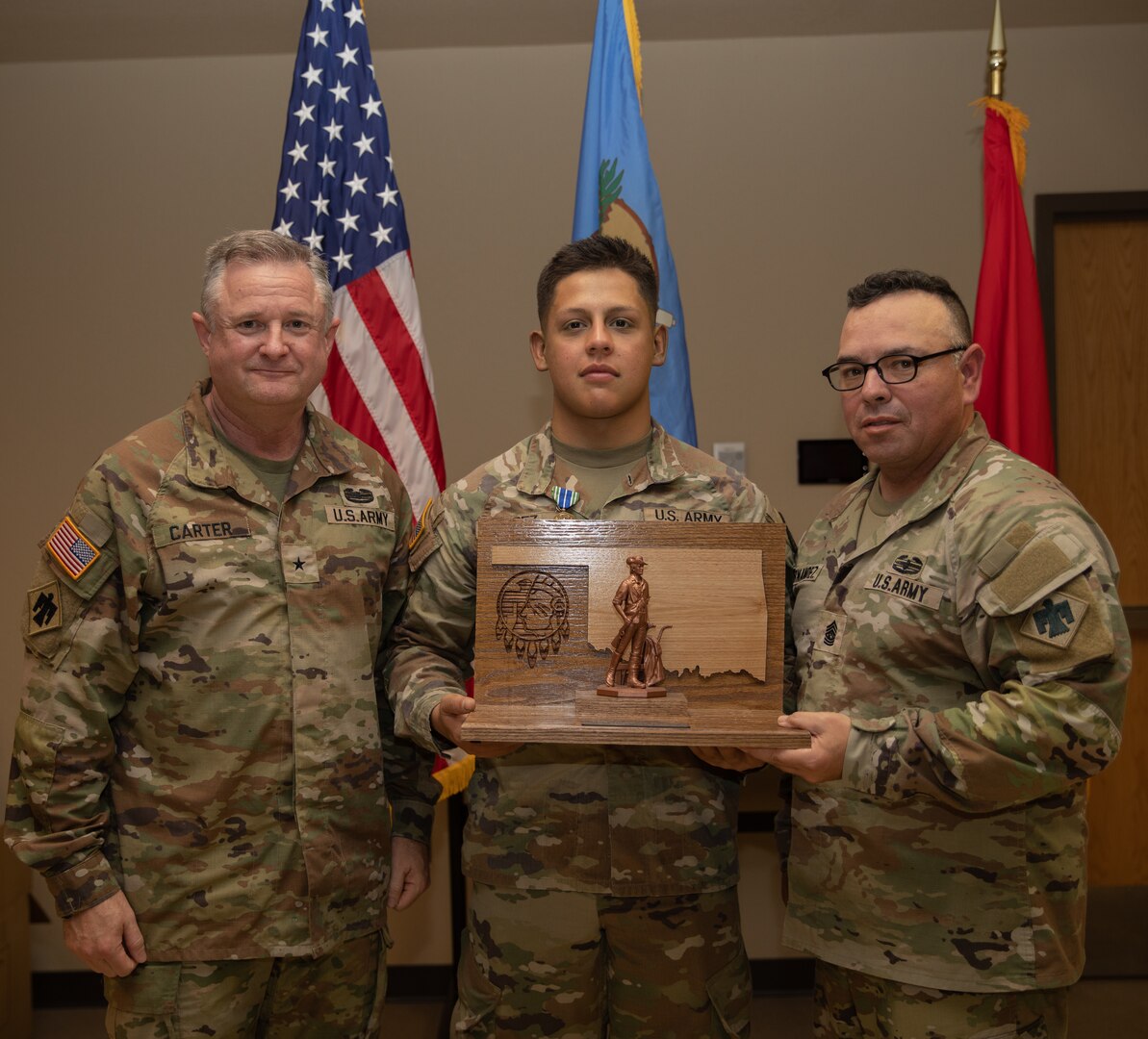 Spc. Juan Lopez, a Stillwater, Oklahoma resident serving as a signal operations support specialist in the 1st Battalion, 160th Field Artillery Regiment, 45th Infantry Brigade Combat Team, poses with Command Sgt. Maj. John Hernandez, the state command sergeant major for Oklahoma, and Brig. Gen. Brad Carter, assistant adjutant general - Army for Oklahoma, after Lopez was named the 2025 Oklahoma Army National Guard Soldier of the Year at Camp Gruber Training Center, Oklahoma, Nov. 8, 2024. (Oklahoma National Guard photo by Spc. Cambrie Cannon)