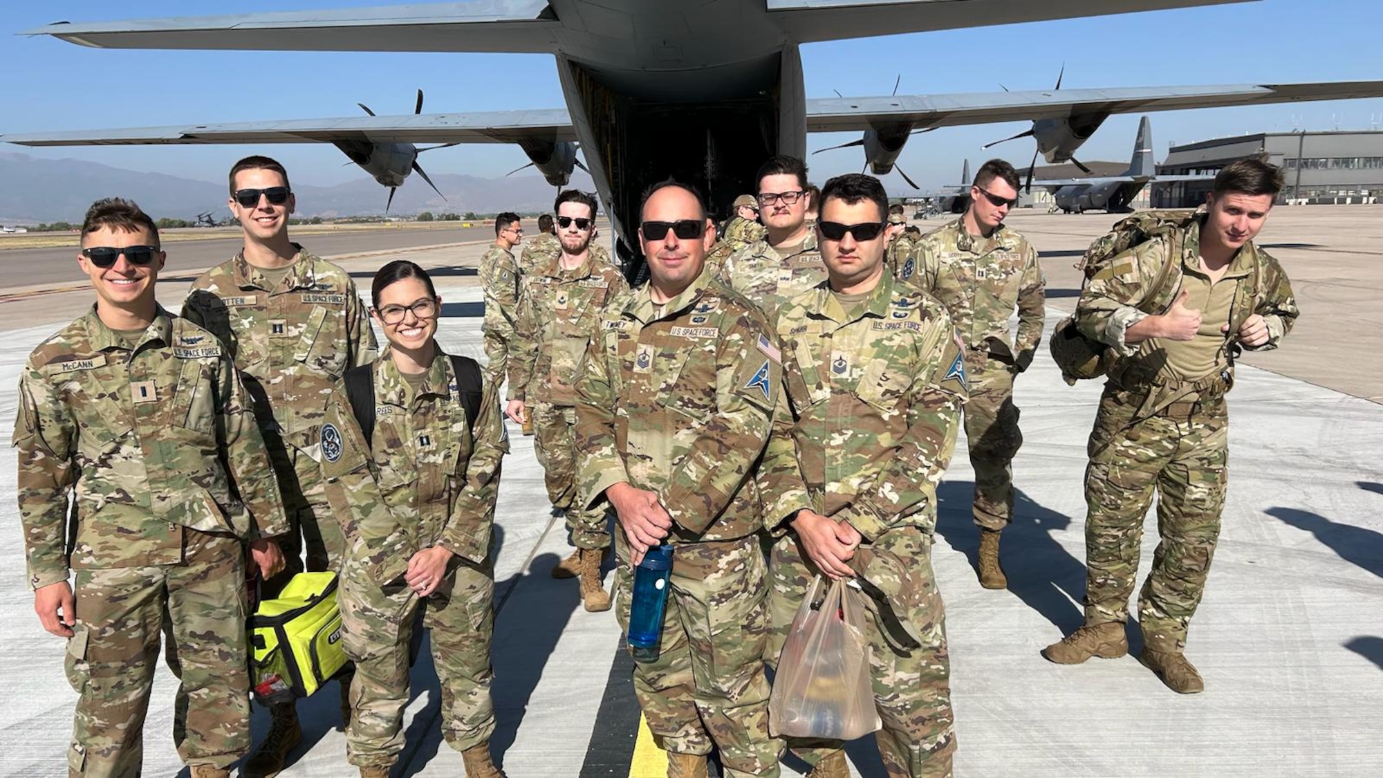 Uniformed members pose for a photo in front of a C-130 before boarding it for a routine exercise.