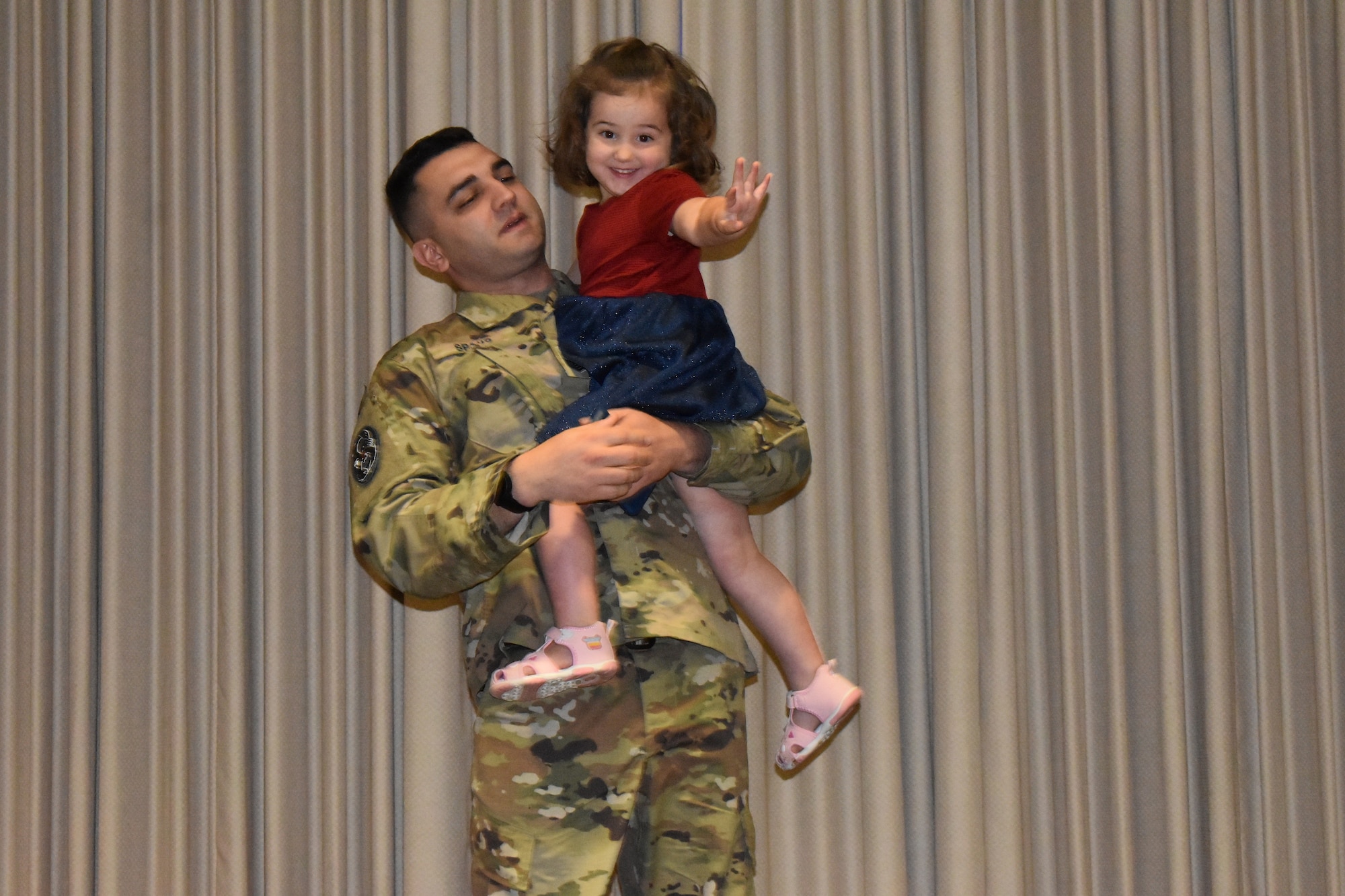 Uniformed members hold his young daughter during his promotion ceremony.