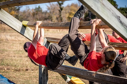 Thunderbird Challenge Program cadets climb over an obstacle during TCP’s field day at Camp Gruber Training Center, Oklahoma, Oct. 25, 2024. The Thunderbird Challenge Program is a 22-week tuition-free program operated by the Oklahoma Military Department and Oklahoma National Guard that provides Oklahoma students in need of school credit recovery with military-based structure, high school or GED classes, college courses, job training and essential life skills. (Oklahoma National Guard photo by Anthony Jones)