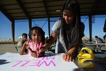 Ellie Patajo, 2 years old, and Elaine Patajo, military spouse, create farwell posters for their loved one at the flightline on Beale Air Force Base, California, Sept. 27, 2024