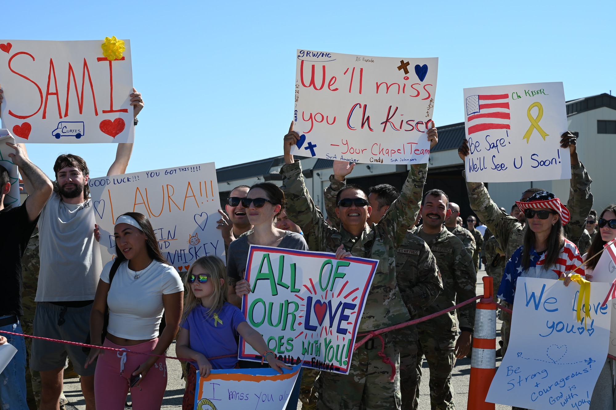 Beale friends and families hold up farewell signs to show support to their military member at the flightline on Beale Air Force Base, California, Sept. 27, 2024.