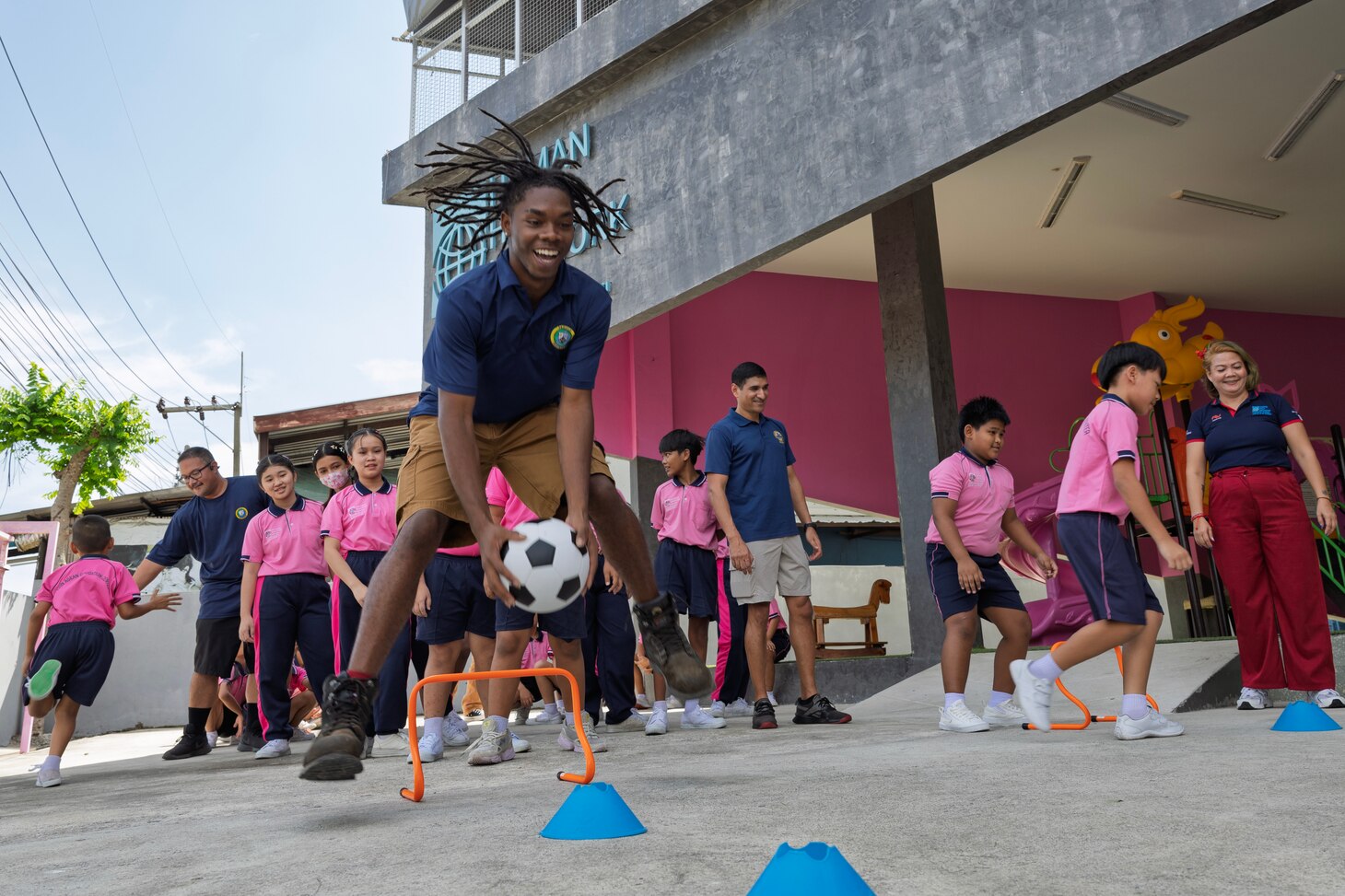 PATTAYA, Thailand—Civilian mariner Tyshon M. Credle, ordinary seaman assigned to expeditionary fast transport ship USNS City of Bismarck (T-EPF 9), leaps during a game at a community outreach event with children of the Learning Center of the Human Help Network Foundation in Pattaya, Thailand, Nov. 7, 2024. (U.S. Navy photo by Grady T. Fontana)