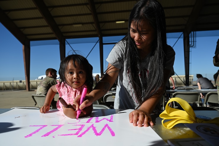 Ellie Patajo, 2 years old, and Elaine Patajo, military spouse, create farwell posters for their loved one at the flightline on Beale Air Force Base, California, Sept. 27, 2024