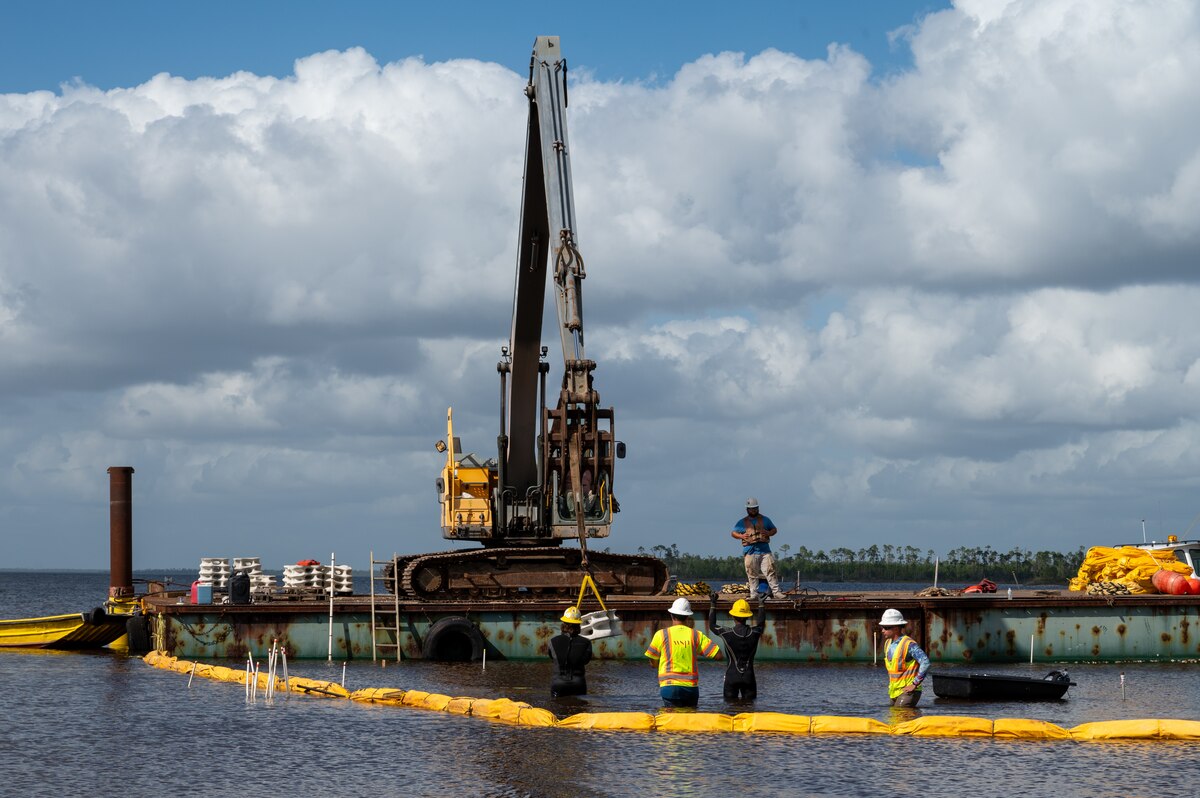 A group of contactors install a segment of concrete modules near the coastline of Tyndall Air Force Base