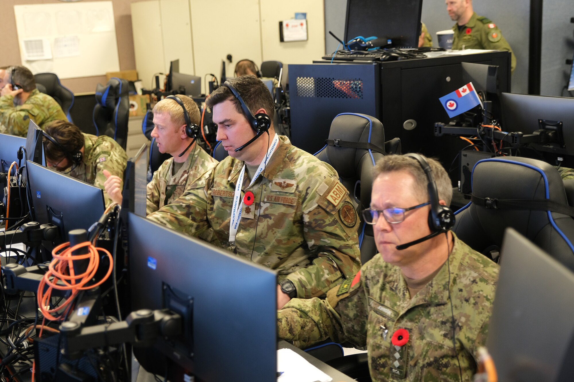 uniformed military members talking near flight simulators