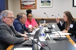 Smith sits across a table from three other people