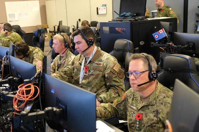 uniformed military members talking near flight simulators