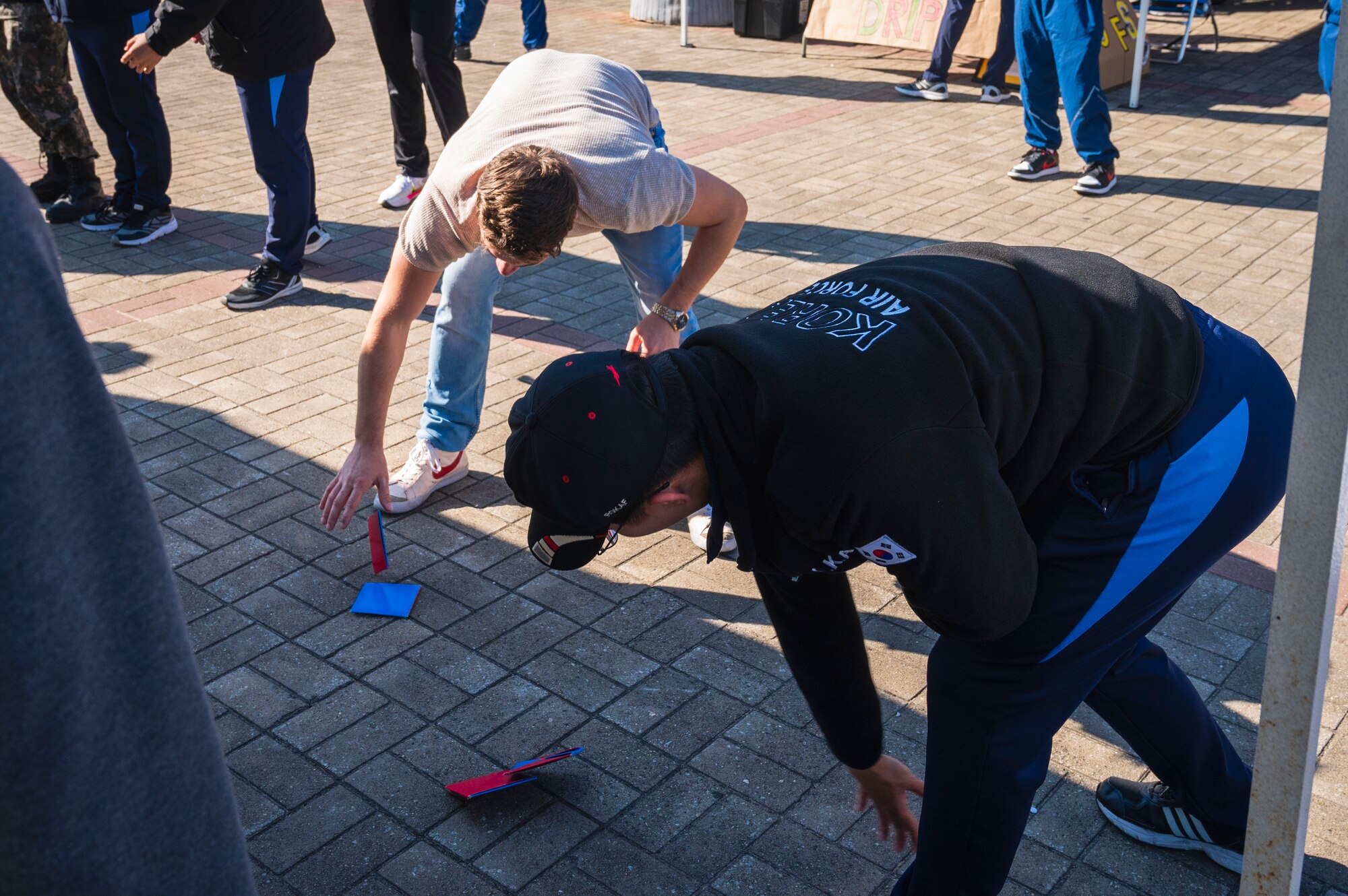 U.S. Air Force Staff Sgt. Nataniel Garcia, left, 8th Communications Squadron non-commissioned officer in charge of network infrastructure and Republic of Korea Air Force Staff Sgt. Seongnim Pak, 38th Information Communication Squadron phone operator, play “Ddak-ji”, a traditional Korean game during Friendship Day at Kunsan Air Base, R.O.K.