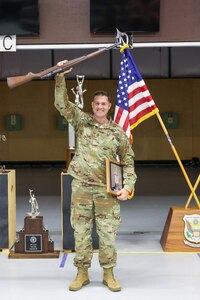 Man in U.S.A. uniform celebrating victory in front of American flag.