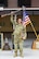 Man in U.S.A. uniform celebrating victory in front of American flag.