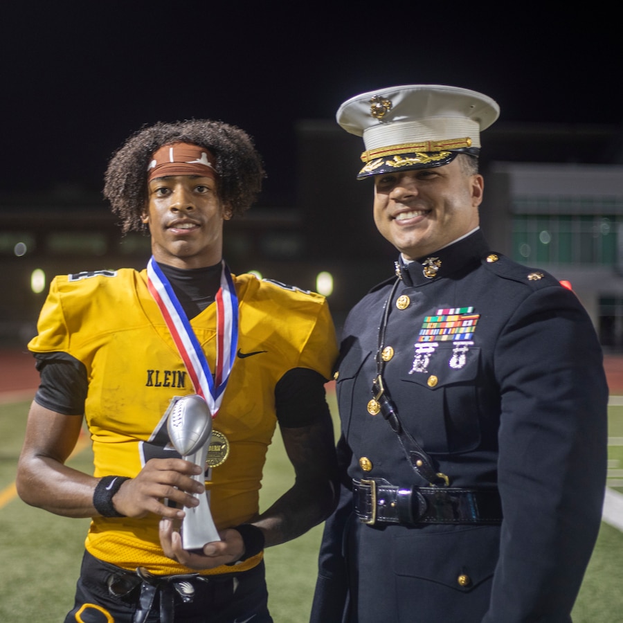 U.S. Marine Corps Maj. Jordan Eddington, commanding officer of Recruiting Station Houston, 8th Marine Corps District, poses for a photo with Courtland Guillroy, a football player with Klein Oak High School, pose for a photo during the Klein Oak High School vs. Klein Collins High School football game with Great American Rivalry Series at Klein Memorial Stadium in Spring, Texas, Oct. 4, 2024. Marines with Recruiting Sub Station Spring, RS Houston, held pull-up challenges, gave away t-shirts, and presented awards to athletes and the winning team. (U.S. Marine Corps photo by Sgt. Ryan H. Pulliam)