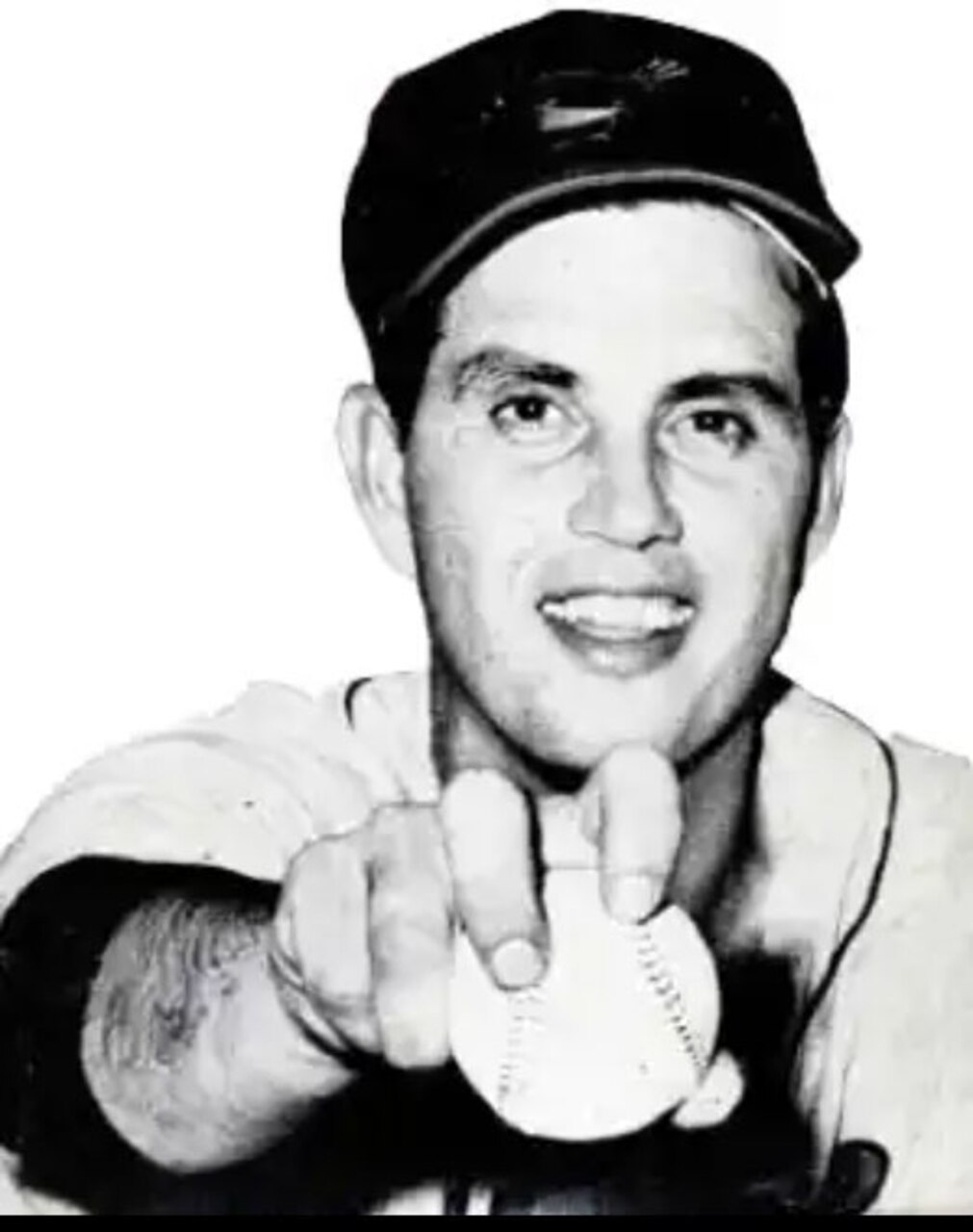 A baseball player extends his arm with a baseball.