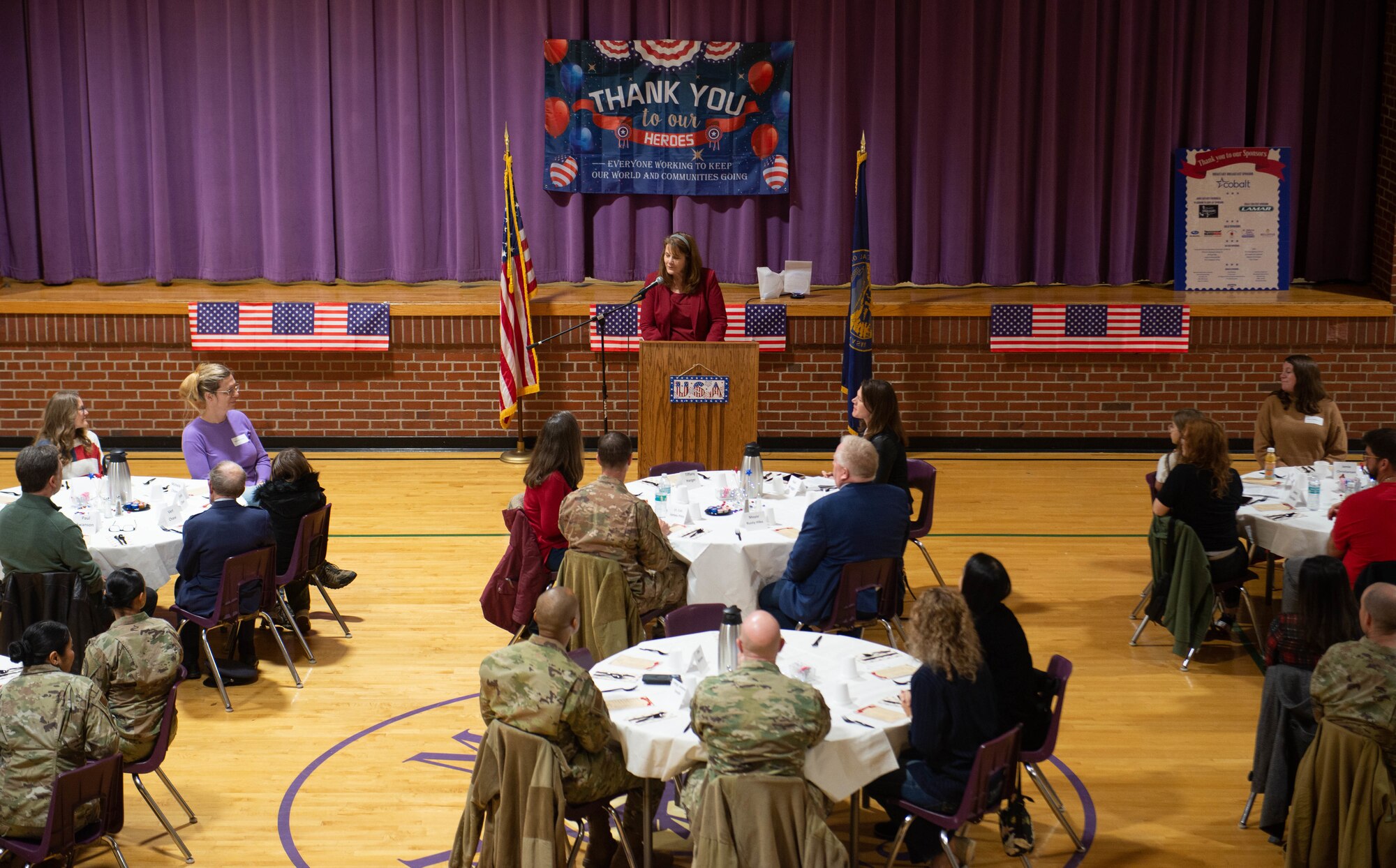 Woman speaks at podium during Veterans Day parade breakfast