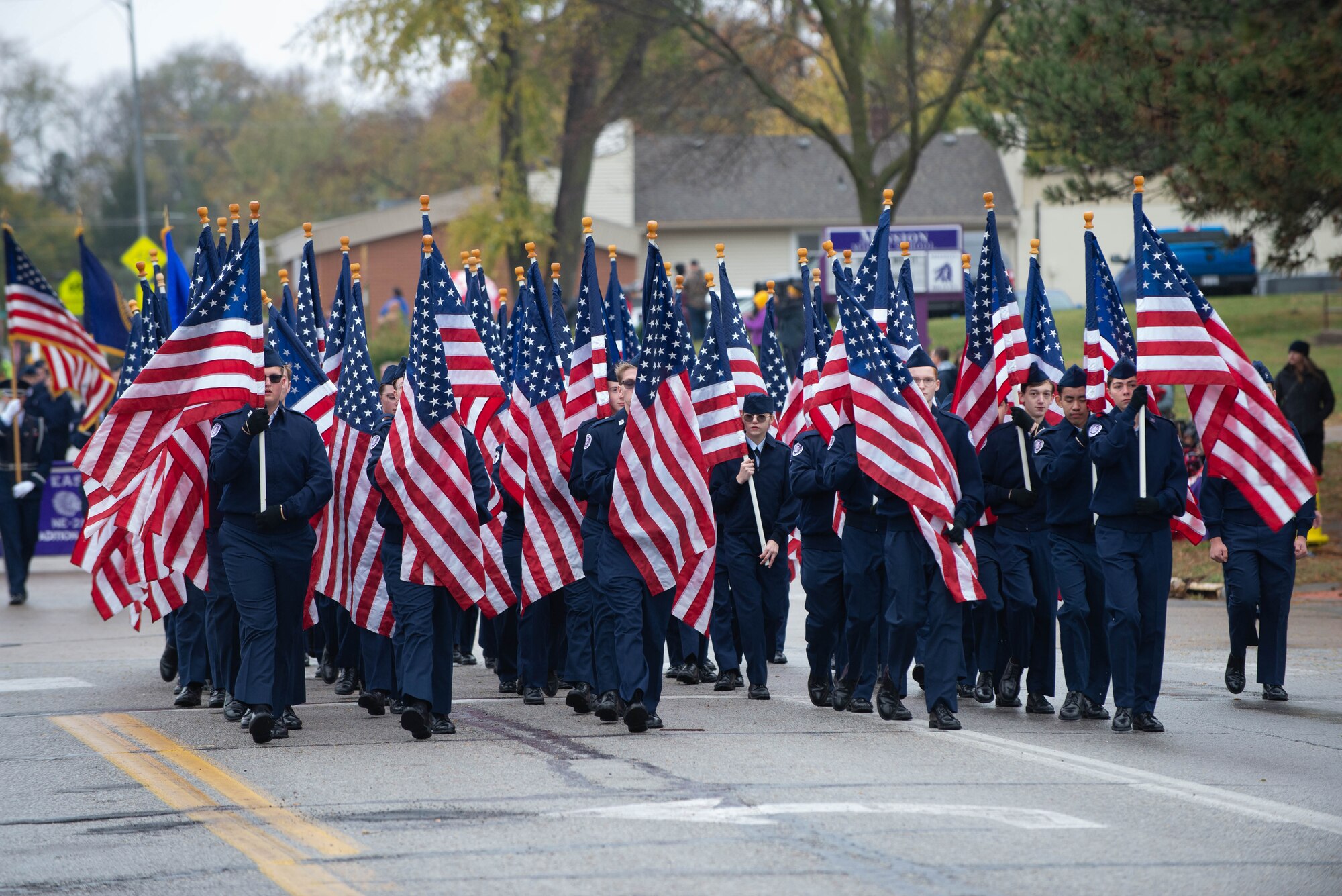 People holding flags while walking in Veterans Day parade