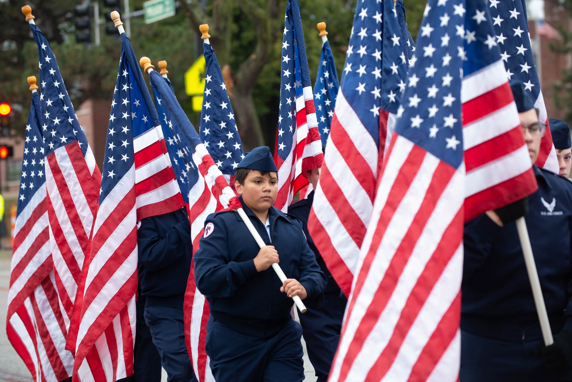 People holding flags while walking in Veterans Day parade