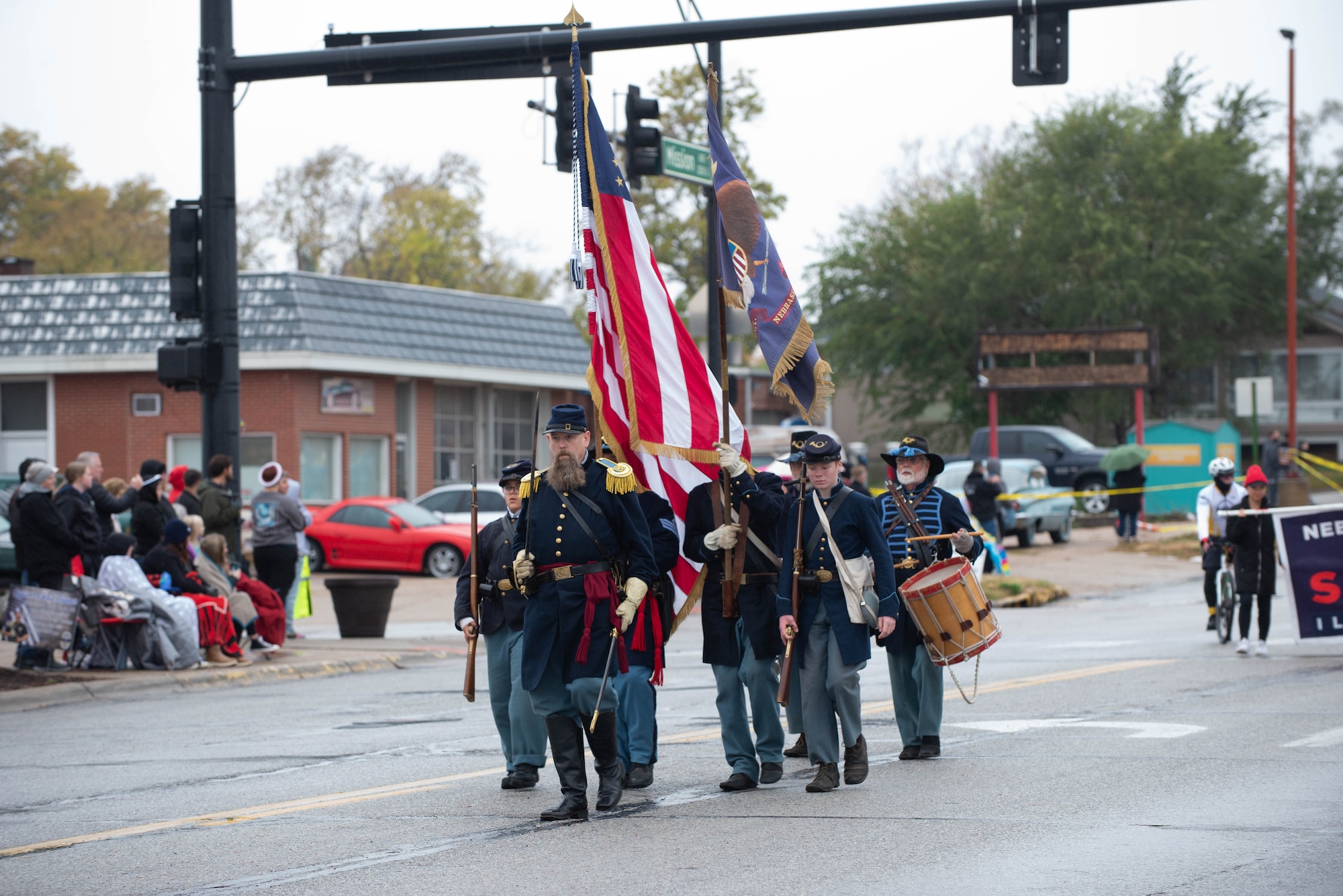 People walk down street, while holding flags, during Veterans Day parade
