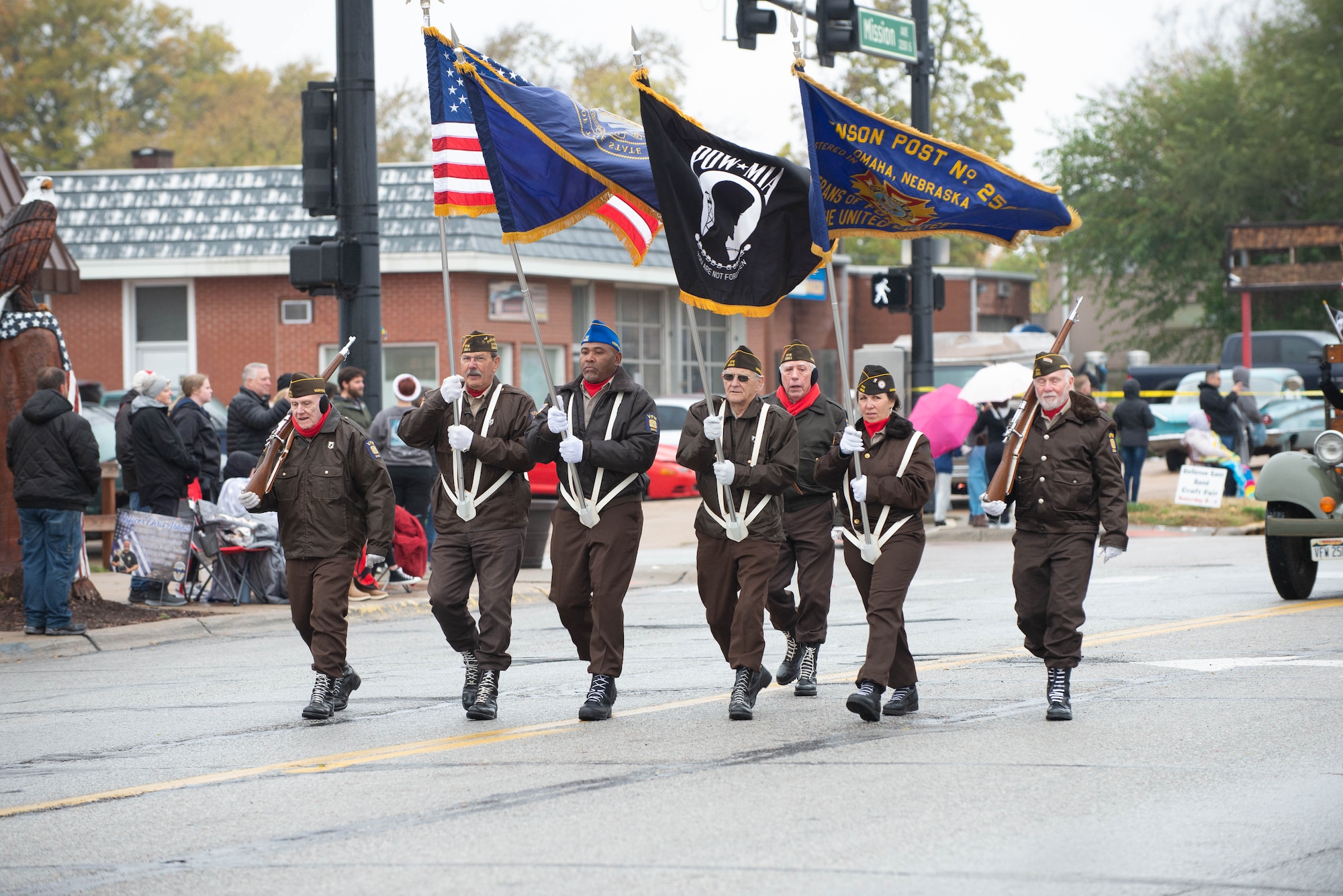People walk down street, while holding flags, during Veterans Day parade