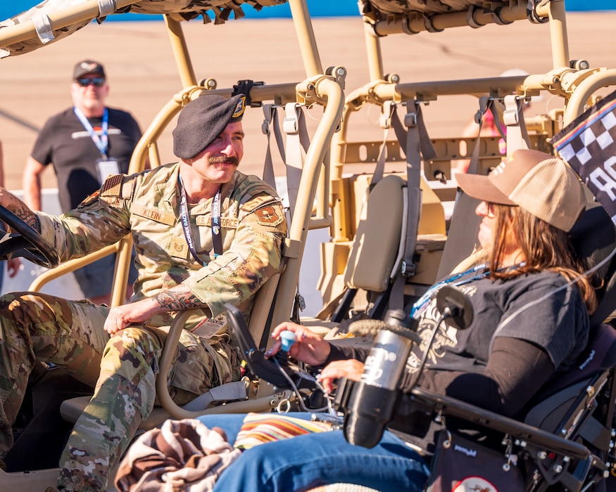 U.S. Air Force Tech. Sgt. Alexander Klein, 56th Security Forces Squadron unit trainer, speaks with a NASCAR enthusiast at a military vehicle display during the NASCAR Championship pre-race events November 10, 2024, at Phoenix Raceway in Avondale, Arizona.