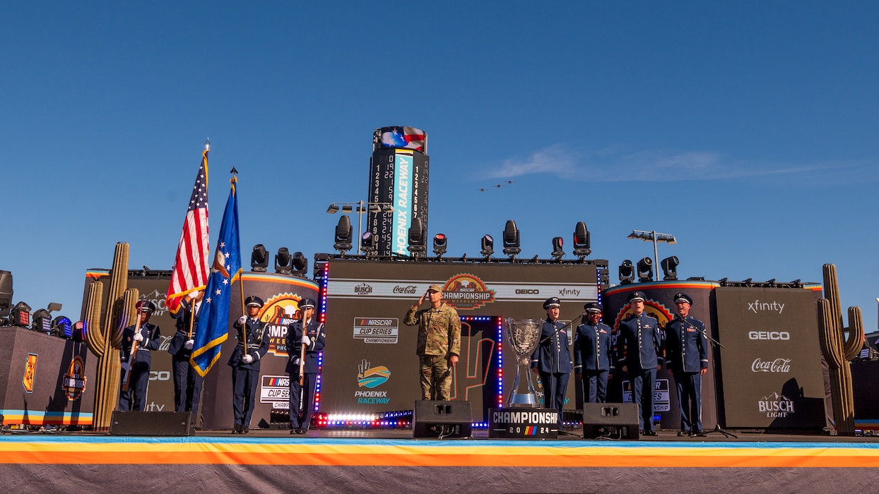 Three A-10C Thunderbolt II’s assigned to the Tucson Air National Guard, honor guardsmen assigned to the 56th Fighter Wing (left), the Air Force Singing Sergeants (right), and U.S. Air Force Air National Guard Major Nathan Tarr (center), 161st Air Refueling Wing chaplain, perform the opening ceremony during the NASCAR Championship pre-race events November 10, 2024, at Phoenix Raceway in Avondale, Arizona.