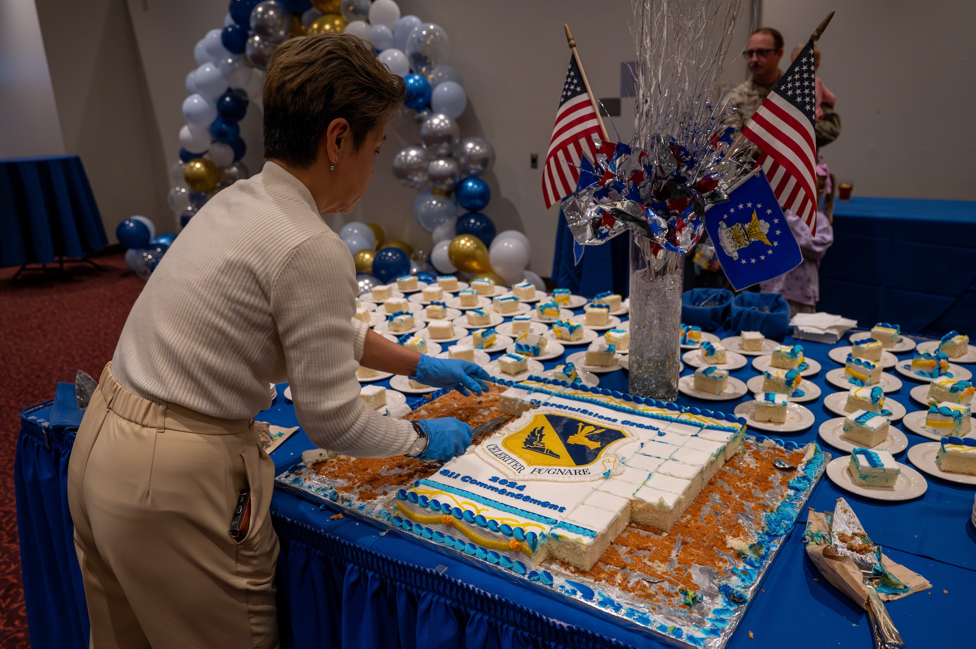 A staff member cuts cake during a commencement ceremony for Community College of the Air Force graduates in the Officers' Club at Yokota Air Base, Japan.