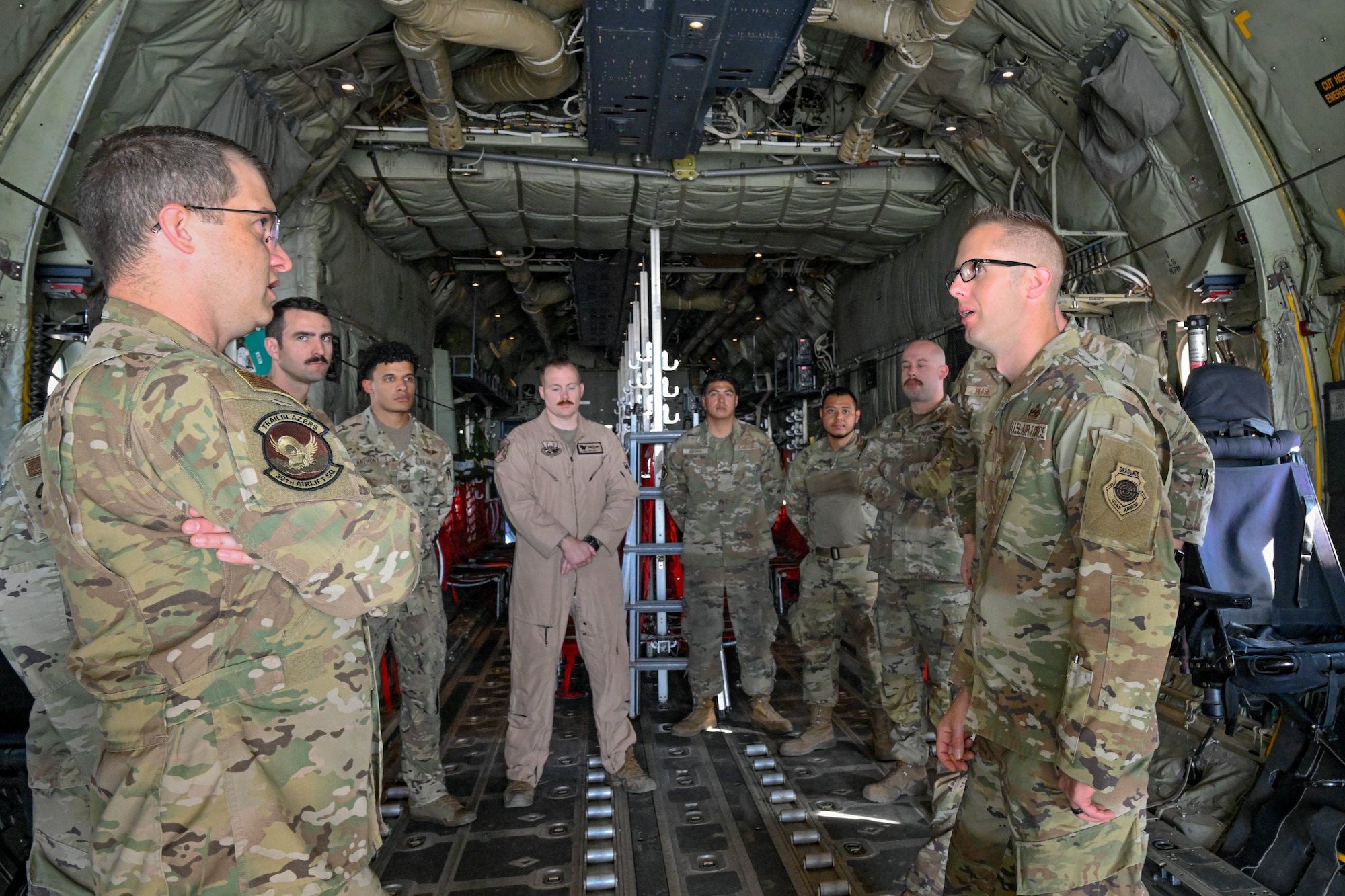 Military members have a conversation in the back of a C-130J Super Hercules aircraft.