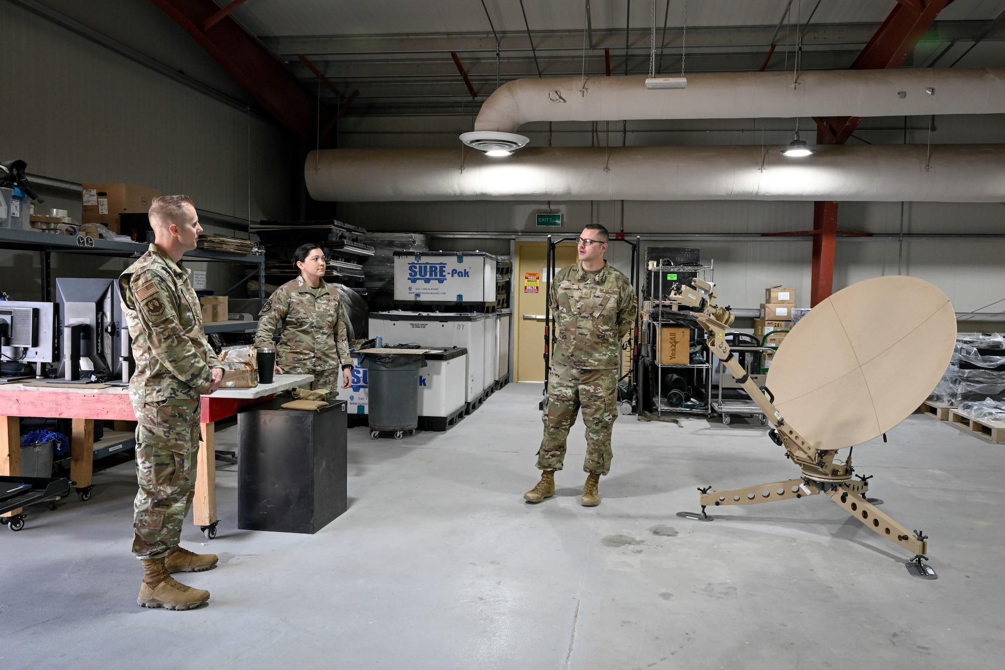 Three military members have a conversation during a visit to their section.
