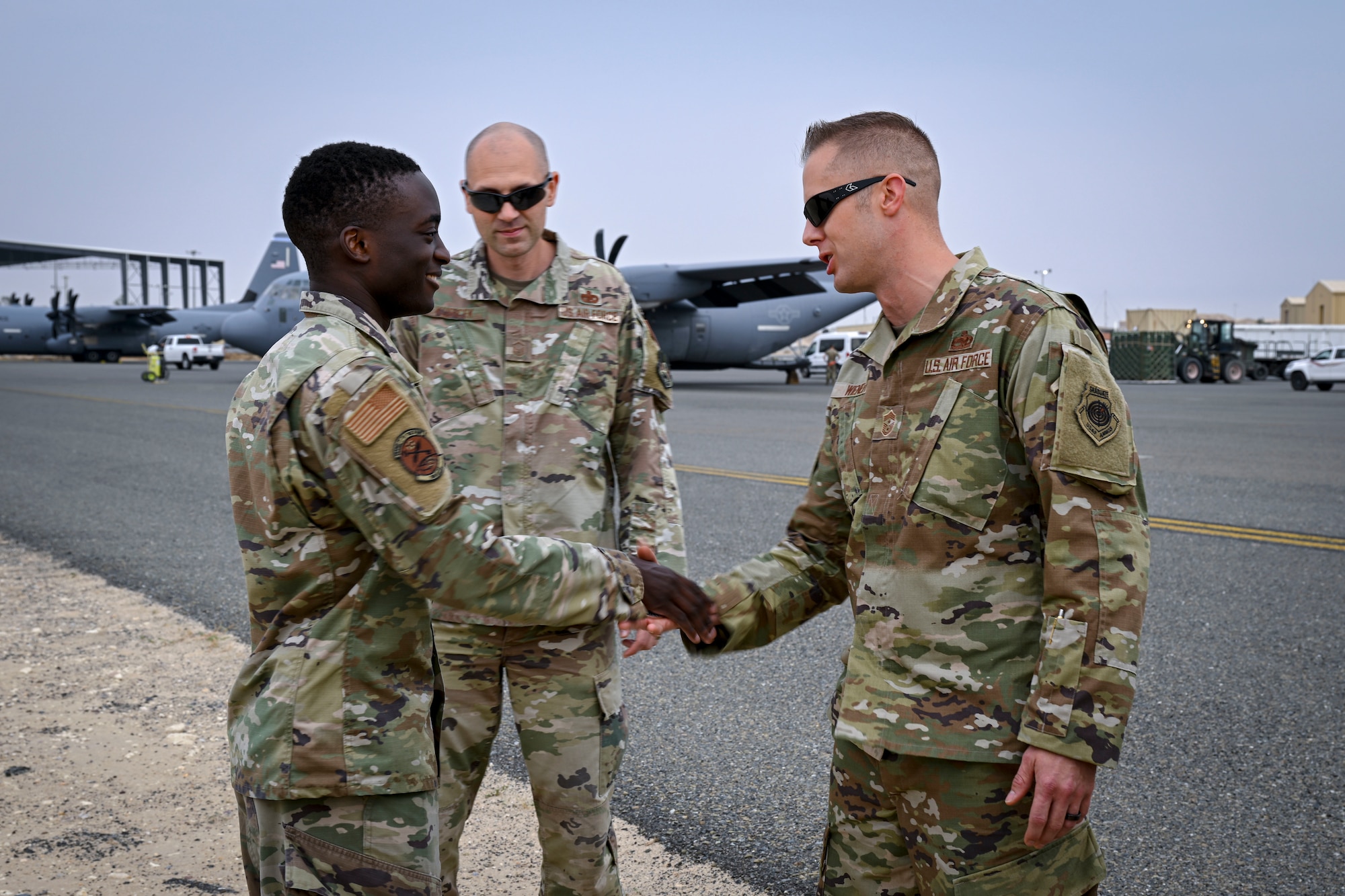 An airman on the left is coined for superior performance by a chief master sergeant during a visit to his work center.