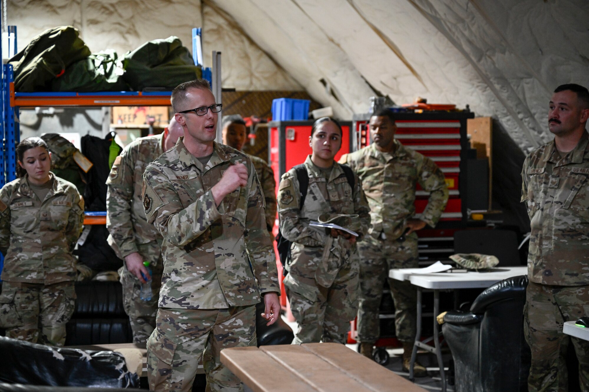 A military members speaks to members during a visit to their work center.
