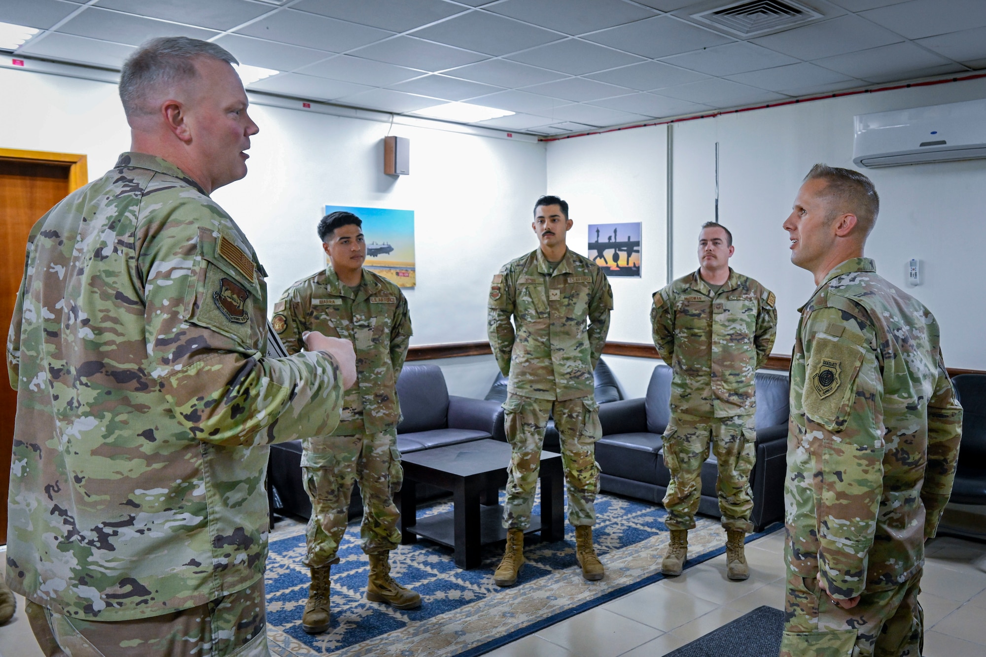 A military member provides an overview of superior performers during a visit to a work center.