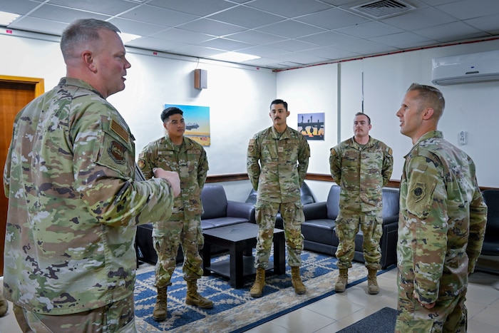 A military member provides an overview of superior performers during a visit to a work center.